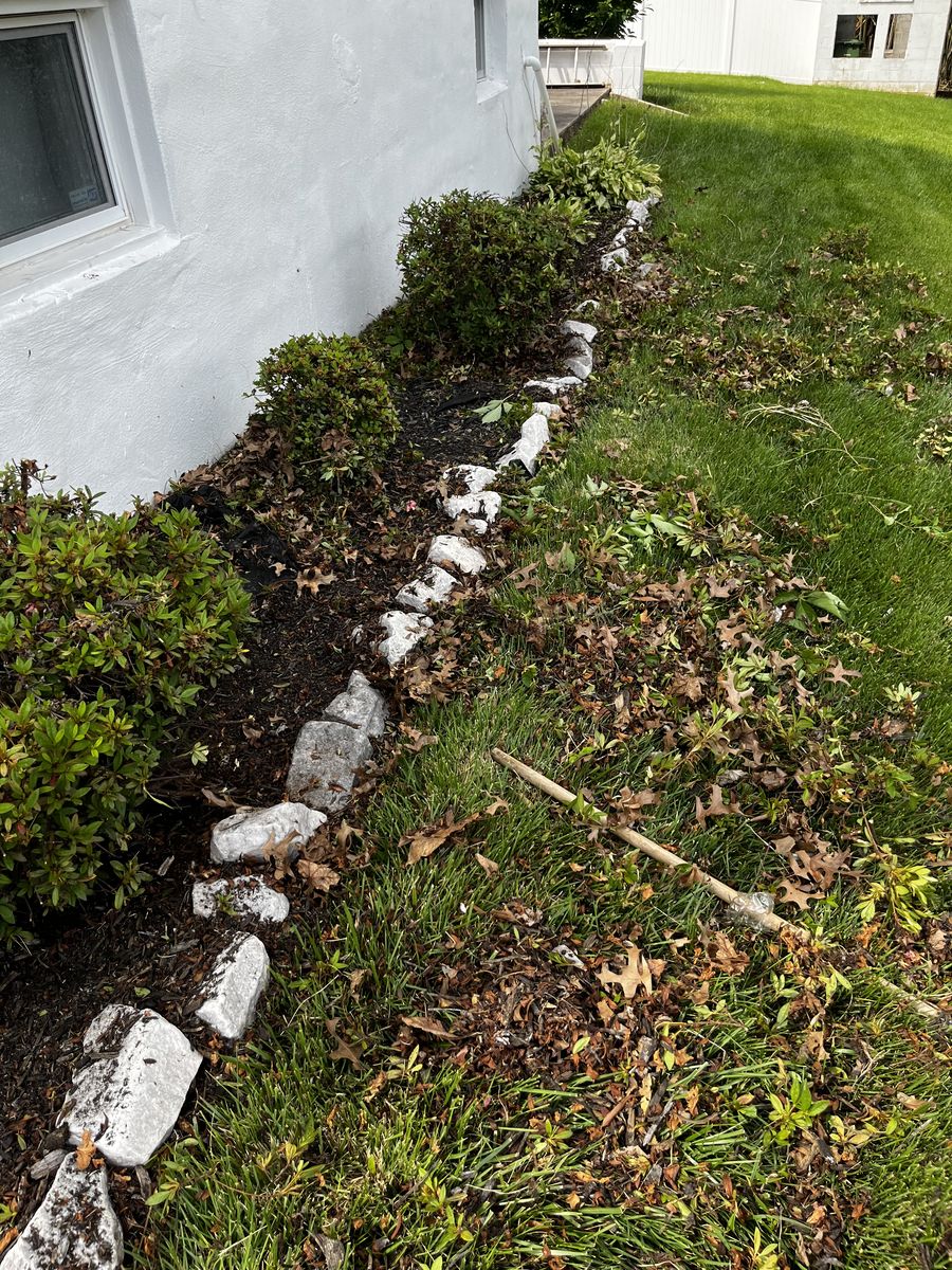 Overgrown side rock bed along a Baltimore home before installation