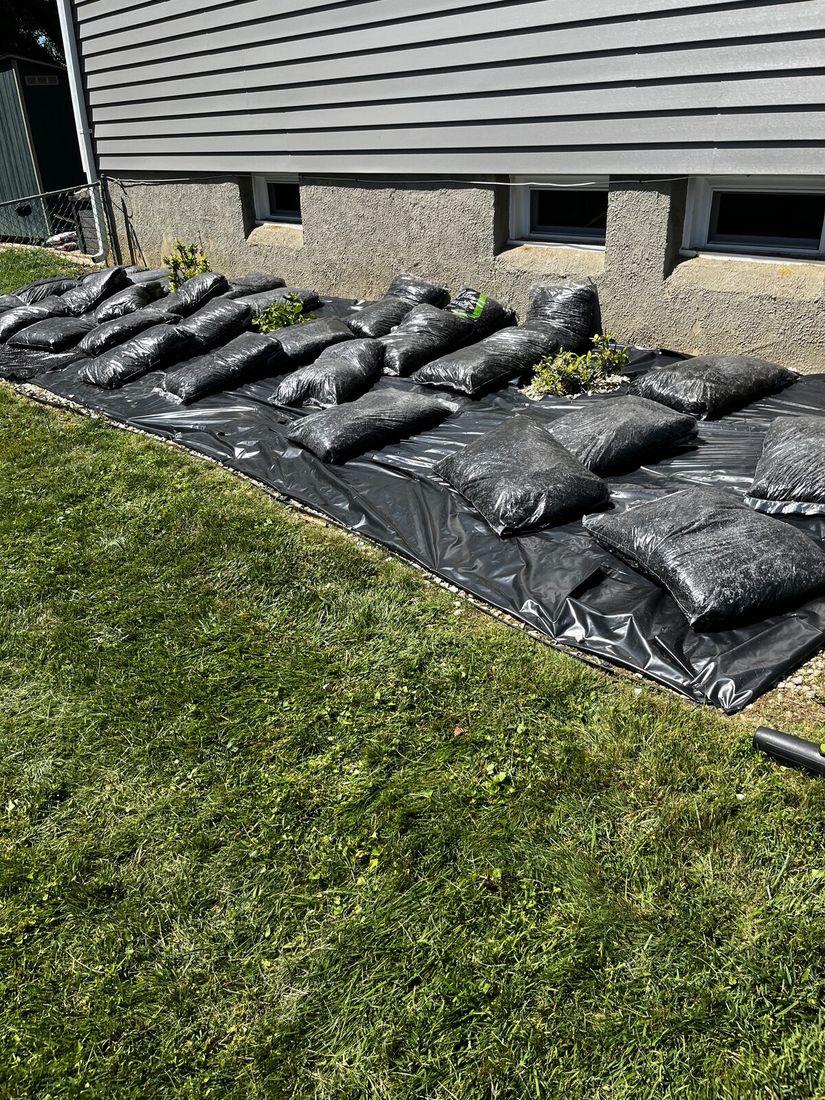 Bags of fresh mulch staged in a row along the prepared bed